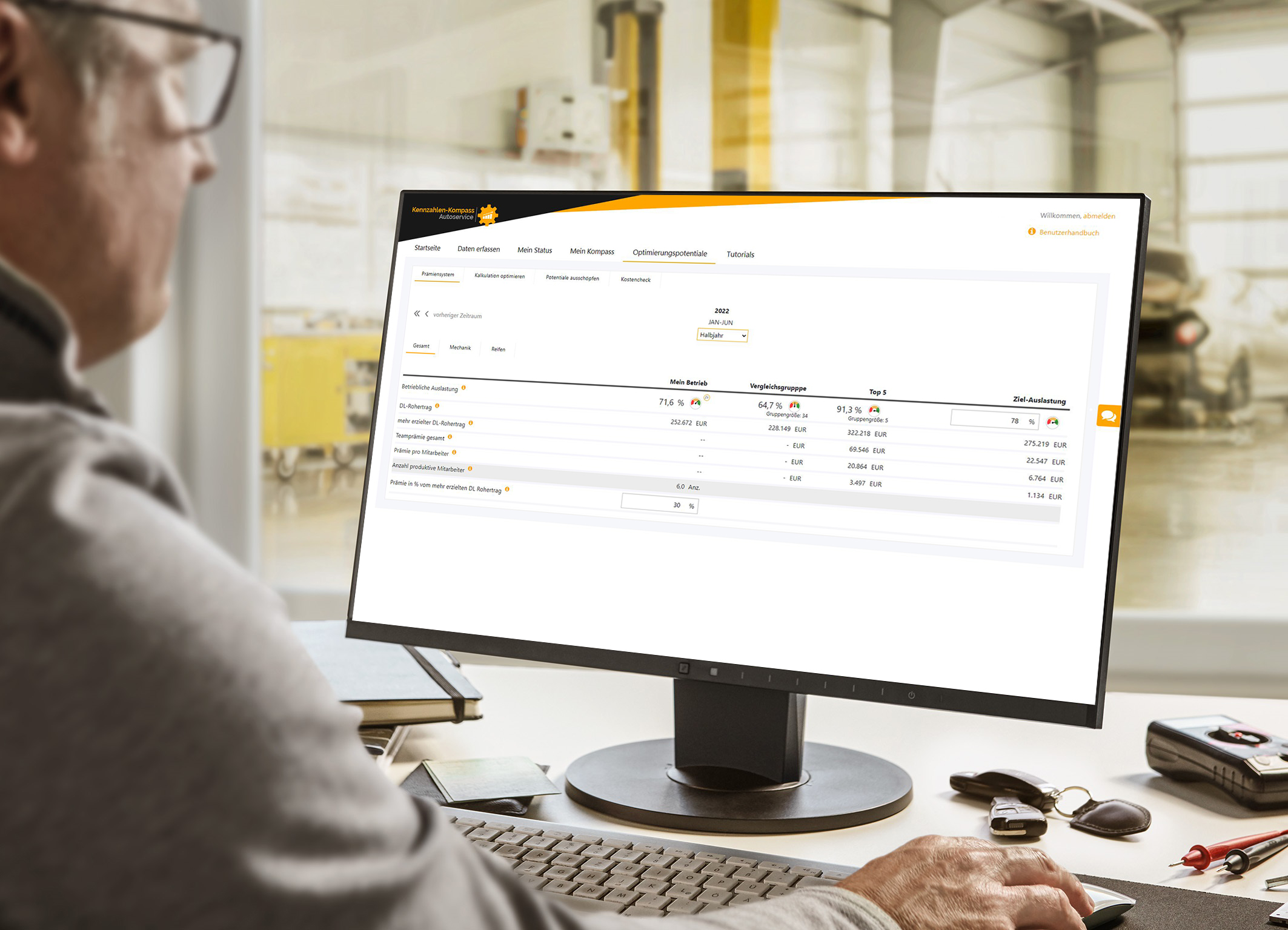 Werkstattmitarbeiter sieht in einen Computerbildschirm, auf dem die Benutzeroberfläche im Kennzahlen-Kompass Autoservice zu sehen ist.